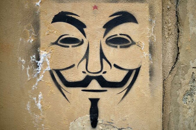 Het gezicht van Guy Fawkes, het symbool van Anonymous, op een muur.