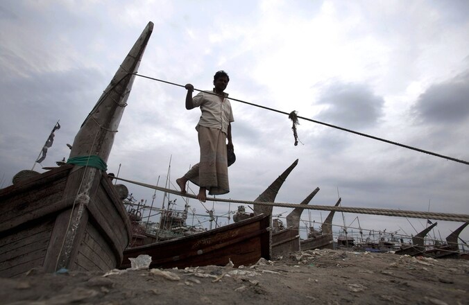 Een visser in Bangladesh maakt zijn vissersboot vast aan de oever van Kornofuli in Chittagong, Bangladesh