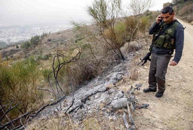 Een Israëlische veiligheidsfunctionaris staat bij de restanten van een van de ingeslagen raketten.