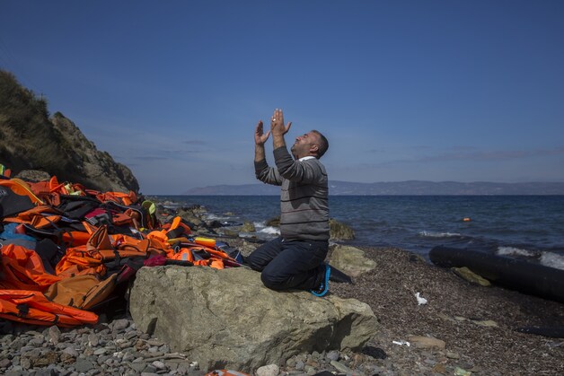 Een vluchteling valt neer om te bidden nadat hij en verschillende anderen het Griekse eiland Lesbos veilig wisten te bereiken.