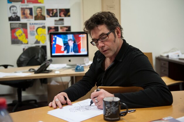 De vermoorde cartoonist Tignous aan het werk op de redactie van Charlie Hebdo.