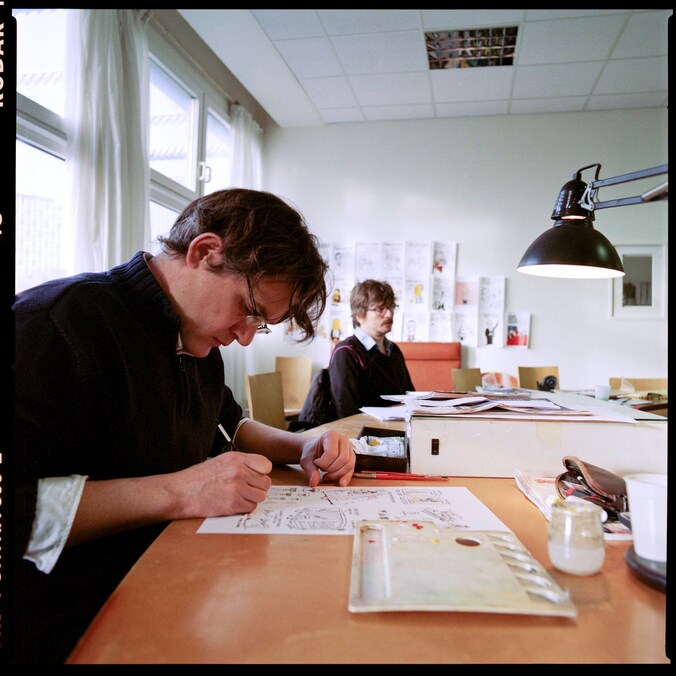 Laurent Sourisseau (Riss) (links) aan het werk op de redactie van Charlie Hebdo. Foto uit 2012.