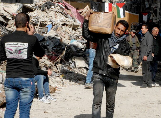 Een inwoner van Yarmouk draagt levensmiddelen met zich mee.