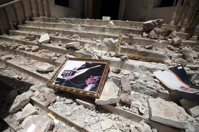 Een portret van koning Salman bin Abdulaziz tussen de brokstukken na een aanval in Sanaa (21 april).