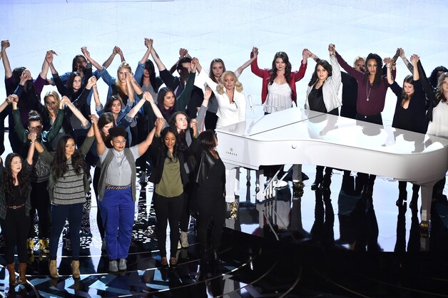 Lady Gaga, omringd door mensen met het opschrift "Not your fault" op de arm.