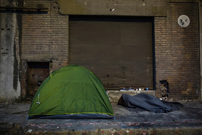 Een vluchteling naast een tent in de haven van Athene.