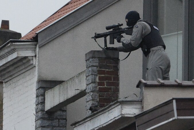 Een lid van de speciale politie-eenheid richt zijn wapen op het 'terreurhuis' in Vorst van waaruit minstens twee verdachten dinsdag het vuur openden op de politie.