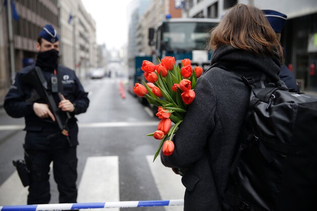 Een vrouw brengt bloemen naar metrostation Maalbeek.