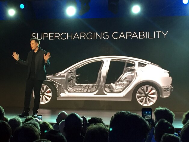 Elon Musk bij zijn Tesla.