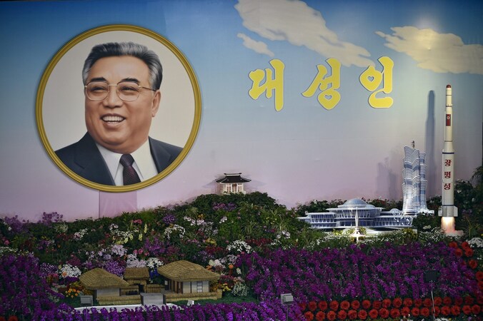 Foto van een bloemenexpositie in Pyongyang waar de Koreaanse grondlegger en een raket naast elkaar staan.
