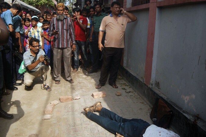 Een beeld van zaterdag: Omstaanders kijken naar het lichaam van een gedode professor in Rajshahi, Bangladesh. Hij kwam op dezelfde manier om het leven als de redacteur van het holebiblad vandaag.