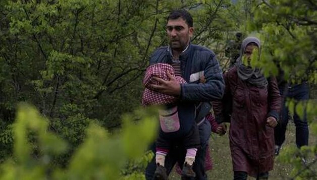 Syrische vluchtelingen steken illegaal de grens over tussen Macedonië en Griekenland.