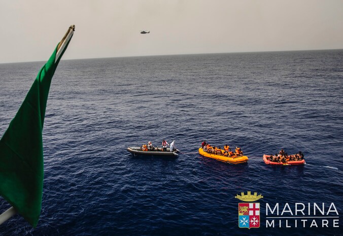 Foto van de Italiaanse kustwacht die boten met migranten oppikt voor de Libische kust.