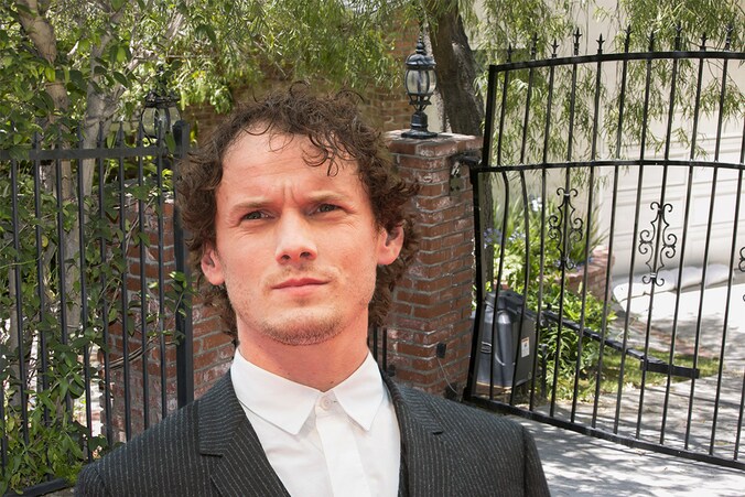 Acteur Anton Yelchin. Achter hem het gedeukte hek bij zijn woning in Los Angeles.