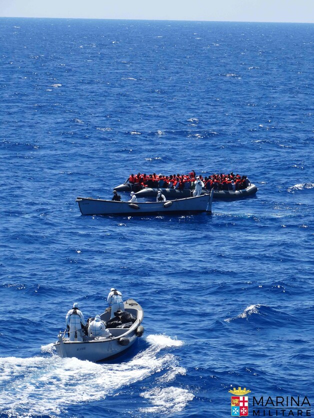 De Italiaanse kustwacht haalt migranten uit bootjes op de Middellandse Zee