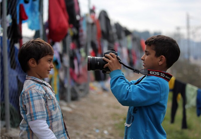 Twee gevluchte kinderen spelen met de camera van een fotograaf.