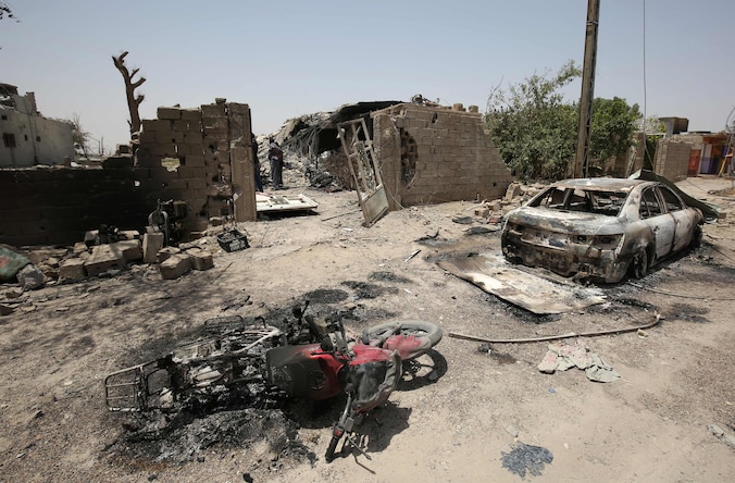 Beschadigde voertuigen en gebouwen in Fallujah na een gewelddadige confrontatie tussen IS-militanten en pro-regeringstroepen.