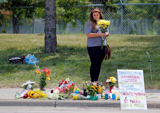 Een vrouw legt bloemen meer voor Philando Castile die tijdens een controle neergeschoten werd door een politieagent.