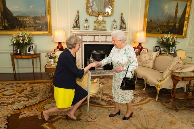 Brits premier Theresa May buigt voor de Queen.