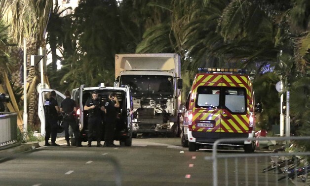 Politieagenten houden de wacht naast de vrachtwagen die in de menigte reed. Het raam lijkt bezaaid te zijn met kogelgaten.