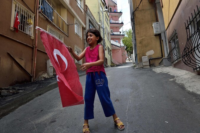 Een meisje speelt met de Turkse vlag in de buurt waar president Recep Tayyip Erdogan geboren is.