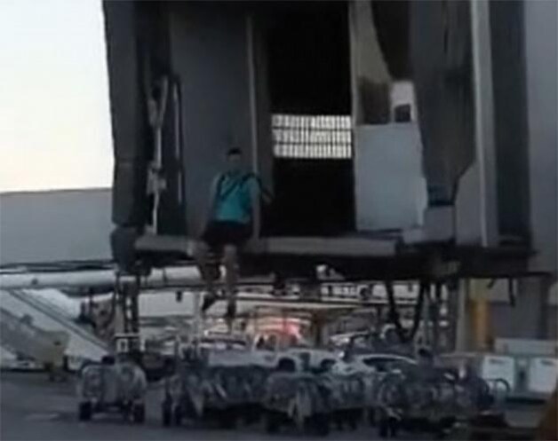 De passagier aarzelt nog even voor hij van de passagiersbrug springt.