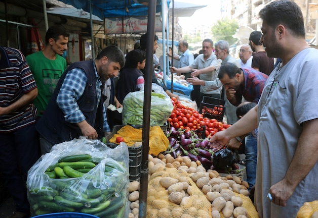 Syriërs kopen groenten op de markt in het bezette deel van Aleppo.