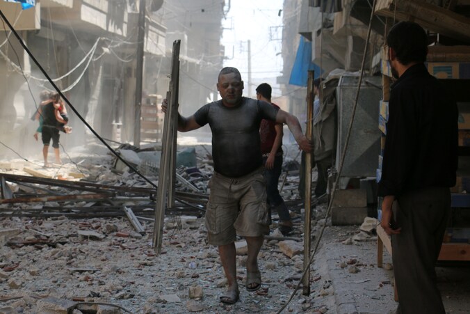 Een man haalt stukken metaal uit het puin, na een nieuw bombardement in Aleppo vandaag.