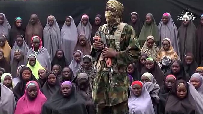 Archieffoto, waarop een Boko Haram-strijder voor een groep gekidnapte meisjes staat.