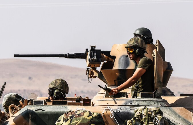 Turkse militairen rijden in een tank Syrië binnen.