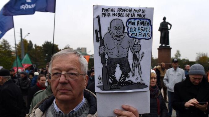 Een man tijdens de demonstratie van zaterdag in Moskou. Hij houdt een bord omhoog met daarop een spotprent van Poetin: 'Poetin voorgedragen voor de Nobelprijs voor de vrede, Ik hou van Donbass en Syrië'