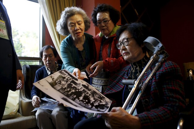 Zuid-Koreaanse vrouwen bekijken oude familiefoto's in afwachting van hun reis naar Noord-Korea.