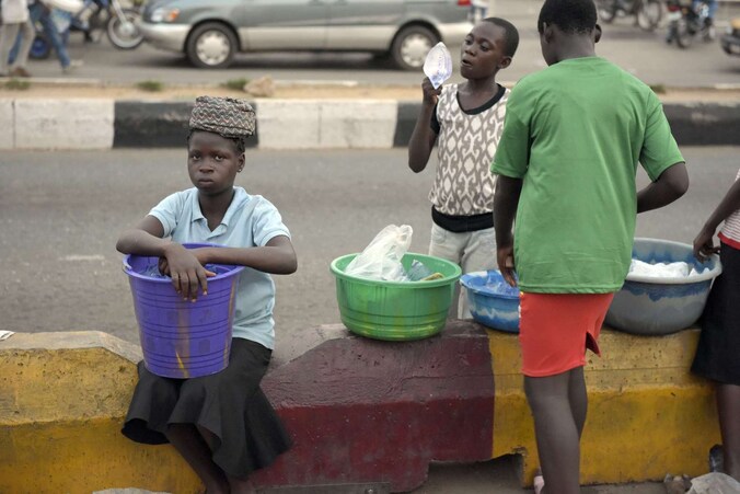 Nigeriaanse kinderen proberen hun waar te verkopen langs de kant van de weg