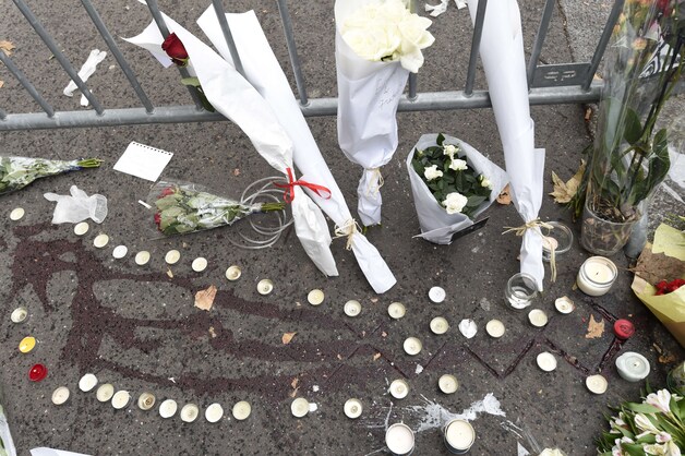 Kaarsen en bloemen aan bloedsporen aan de Bataclan.