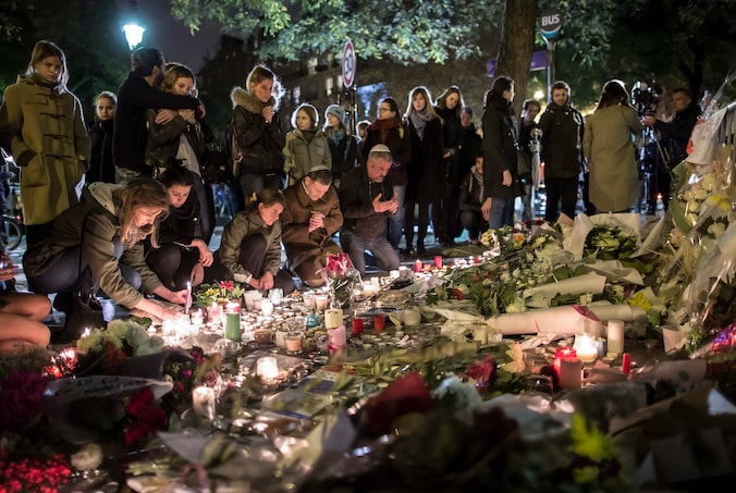 Mensen leggen bloemen en plaatsen kaarsen aan de Bataclan in Parijs als eerbetoon aan de slachtoffers van de aanvallen op vrijdag 13 november.