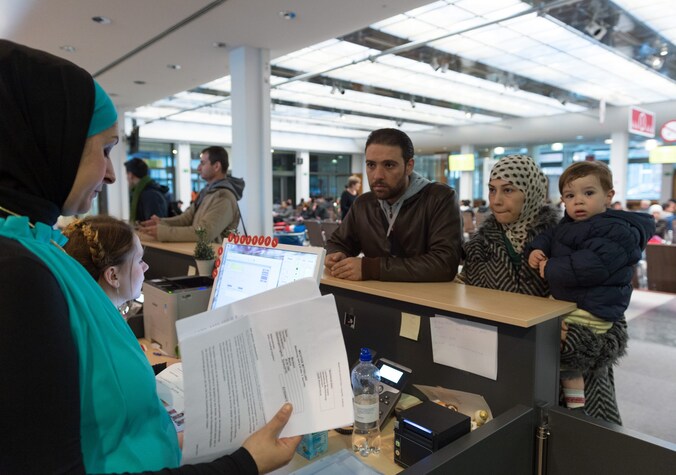 Syrische vluchtelingen spreken met een tolk tijdens hun registratieproces in Duitsland.