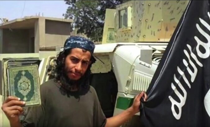 Abdelhamid Abaaoud met een koran en een IS-vlag, beeld uit een niet-gedateerde IS-video.