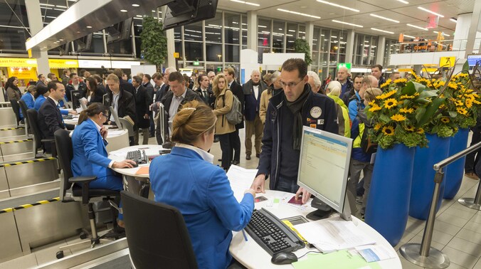 Passagiers staan in de rij om in te checken op Schiphol.