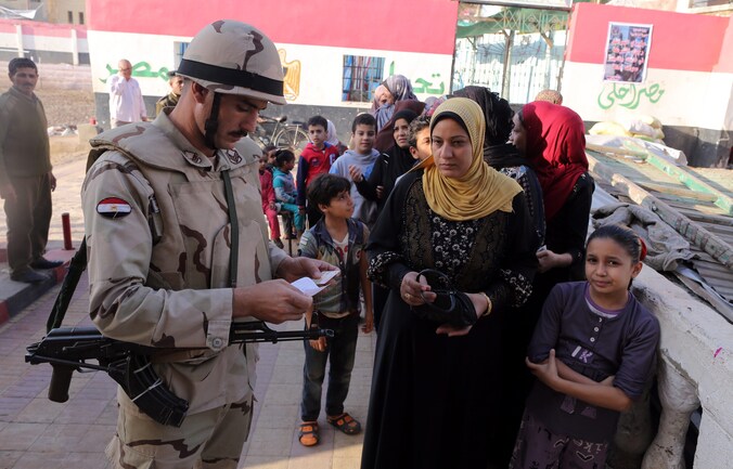 Een Egyptische soldaat checkt het id-bewijs van een kiezer.