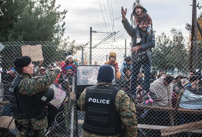 Asielzoekers protesteren achter het hek aan de Grieks-Macedonische grens, vandaag.