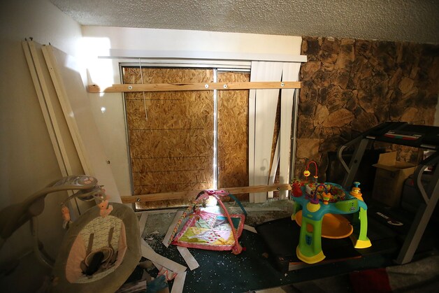 Speelgoed en babyspullen in de woonkamer van Farook en Malik. De ramen werden sinds het incident dichtgemaakt met houten planken.