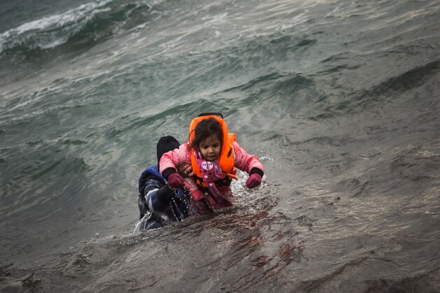Een vrijwilliger helpt een kind naar het strand op het Griekse eiland Lesbos.
