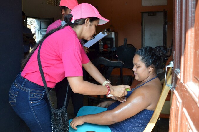 Colombiaanse vrouwen krijgen muggenwerende spray opgespoten.