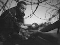 De winnende World Press Photo van een man die een baby doorgeeft via een gat in het hek aan de Hongaarse grens