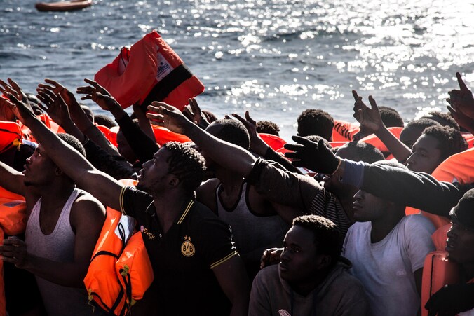 Migranten op weg naar Italië krijgen reddingsvesten aangereikt vanop een reddingsboot van Artsen Zonder Grenzen en SOS Mediterranee.