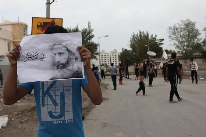Een demonstrant houdt een foto van Nimr al-Nimr omhoog.