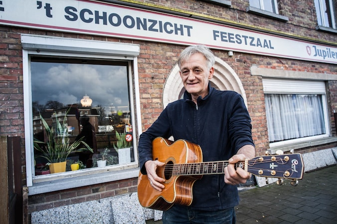 Gido VanGent met zijn trouwe vriend, de gitaar, voor het café.