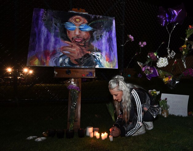 Een fan steekt kaarsjes aan bij een portret van Prince, bij zijn landgoed in Minneapolis.