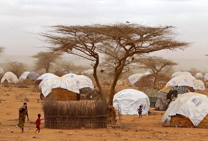 Vluchtelingen wandelen langs hutjes in het vluchtelingenkamp in Dadaab.