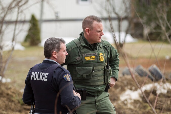 Een agent van de Amerikaanse grenspolitie (links) spreekt met een Canadese grenswacht in de Canadese staat Manitoba.